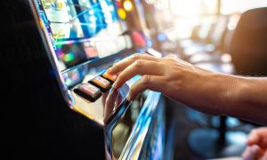 Image of person playing a slot machine, which is among the gambling options at the 14 gas station casinos — or gasinos — in California