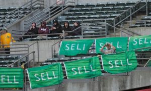 Oakland A's fans with "Sell" signs while ownership finalizes plans to sell the Oakland Coliseum