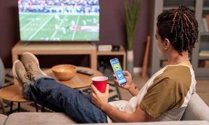a person using a mobile sports betting app while sitting on their couch